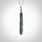 This picture shows a hand carved Inanga Pounamu, jade drop pendant with sterling silver cap and chain. The jade is a very dark green with a shimmer of light blue tones in the stone. It is suspended from a sterling silver clasp and we supply a sterling silver chain. Delivery is free worldwide.